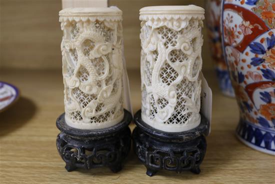 A pair of Chinese carved ivory tusk reticulated vases, carved with dragons among clouds and with carved and pierced hardwood stands